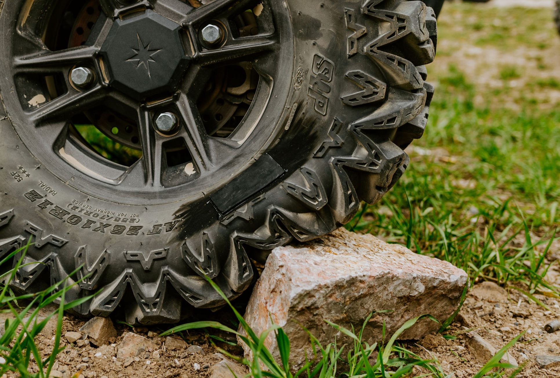 ATV tire sidewall pressed against a rock, illustrating a common cause of tire sidewall damage.