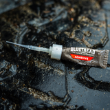 GlueTread tire repair adhesive tube with applicator tip on a wet off-road tire
